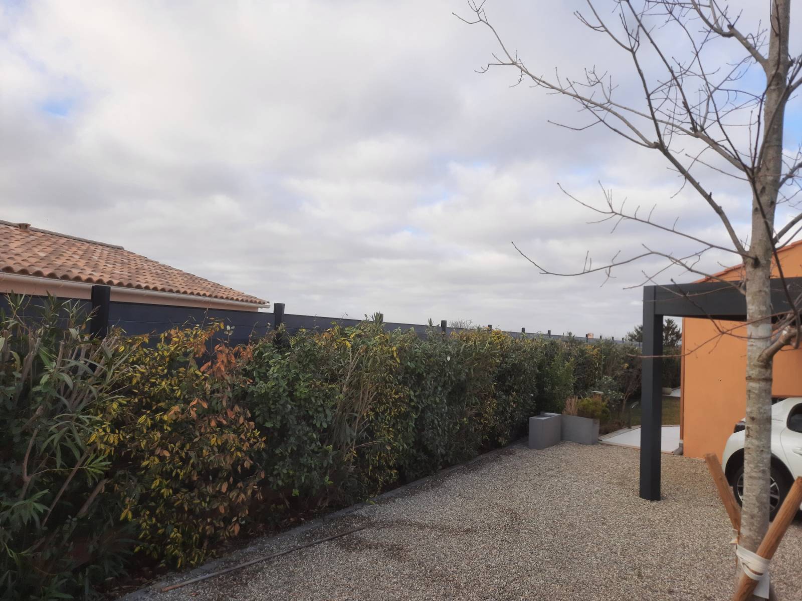 Un cloture en plastique recyclé derrière une haie bien entretenu à pourrières