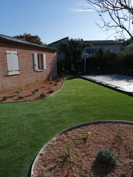 Une création de jardin avec massif fleuri et gazon synthétique dans le var